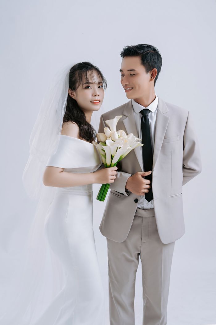 A graceful Asian couple in a studio setting, showcasing wedding attire and joy.